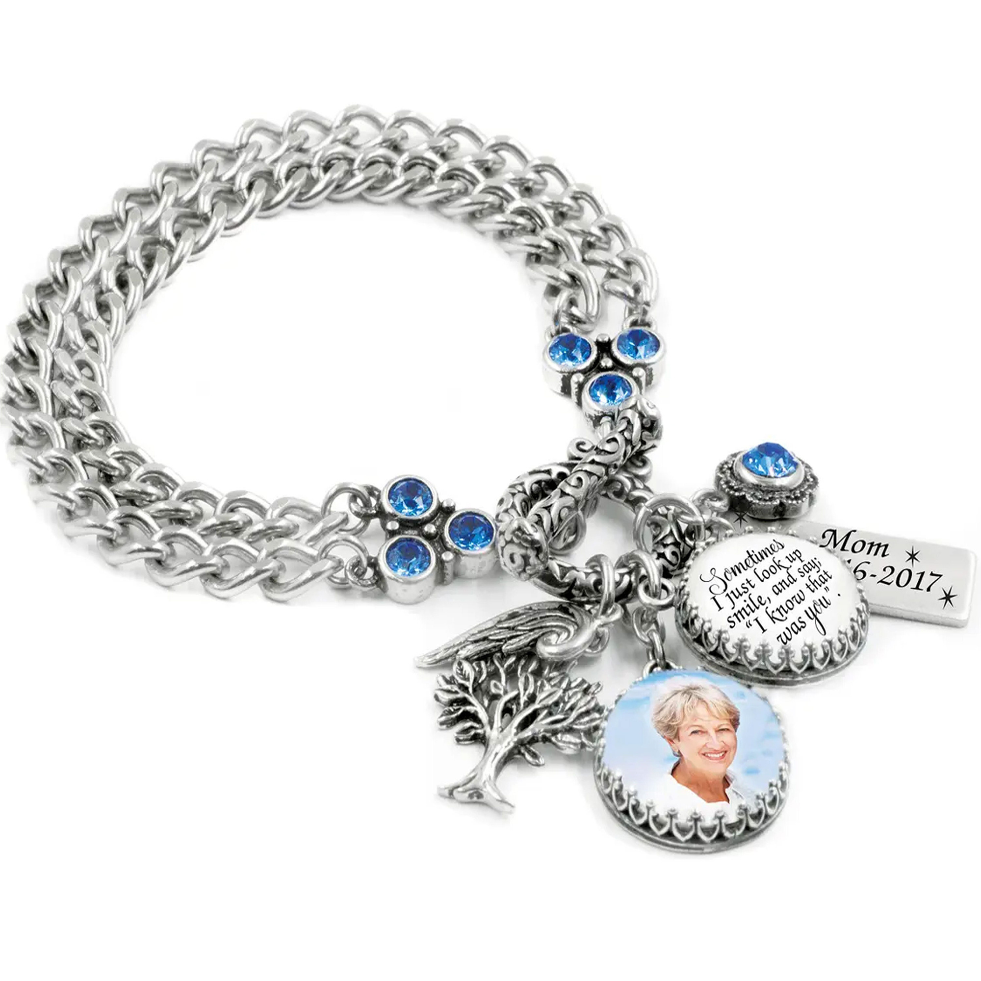 Close-up of a silver chain bracelet with blue gemstones and round photo charms showing a smiling woman, on a white background.