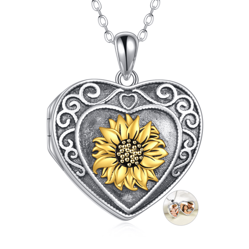 Silver heart-shaped locket pendant with intricate white scrollwork, a gold sunflower center, and a silver chain attached above.