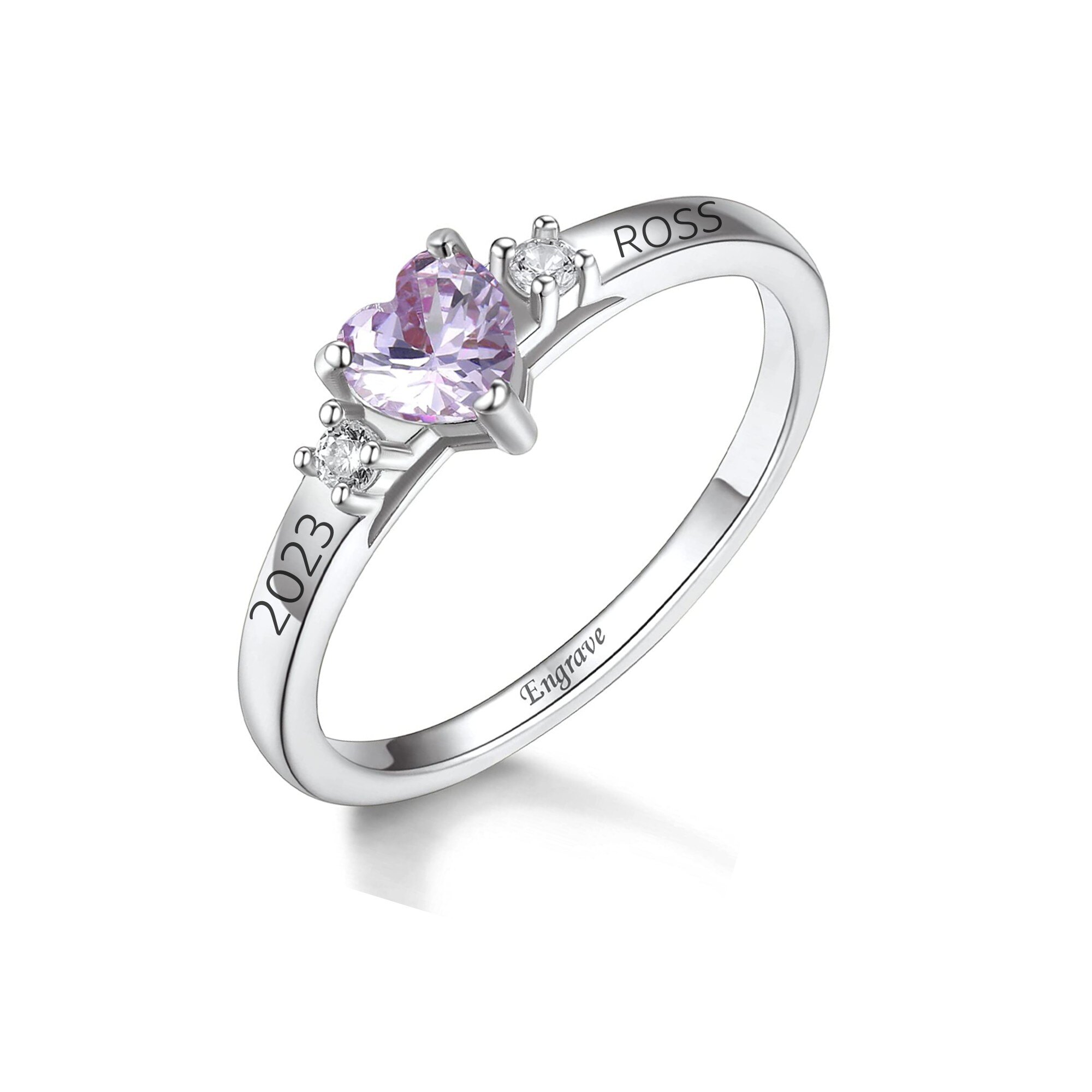 Close-up of a silver ring with a pink heart-cut gemstone and small diamonds, shown at an angle with engraving on the inner band clearly visible.