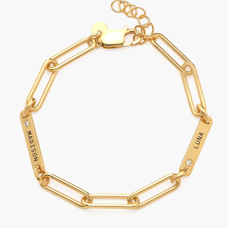 Gold bracelet with rectangular link segments and two name tags reading 'MADISON' and 'LUNA', each with a small gemstone, on a lobster clasp chain