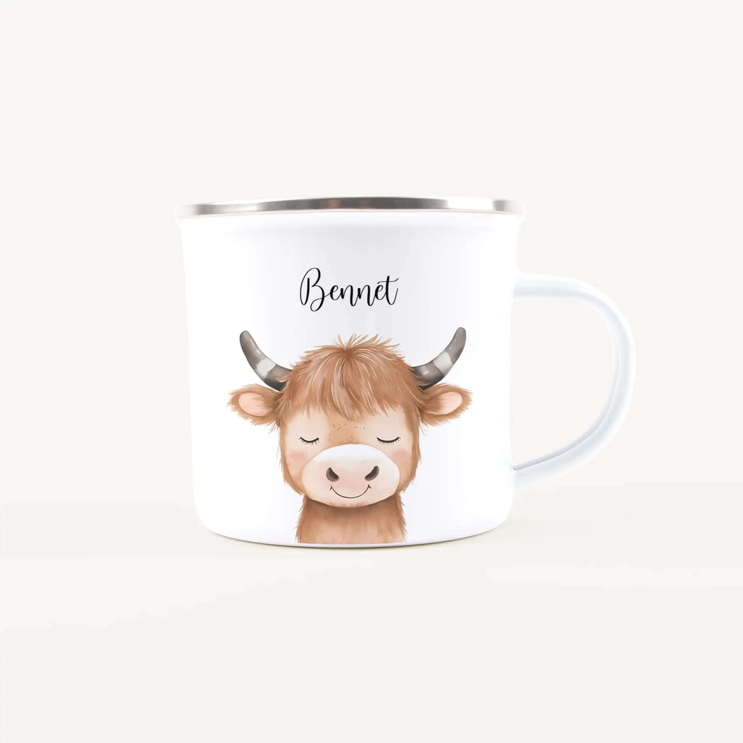 White ceramic mug featuring a cute cartoon cow with curved horns and a closed-eye expression, plus the name Bennett scripted on the side.