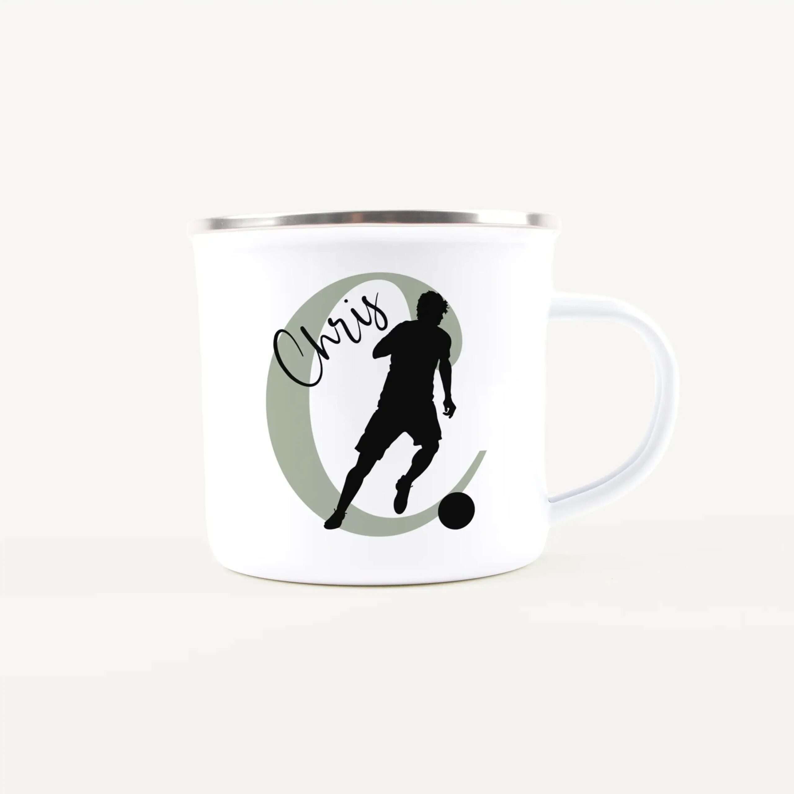 White mug with a black silhouette of a person kicking a ball inside a pale green circle and cursive text nearby.