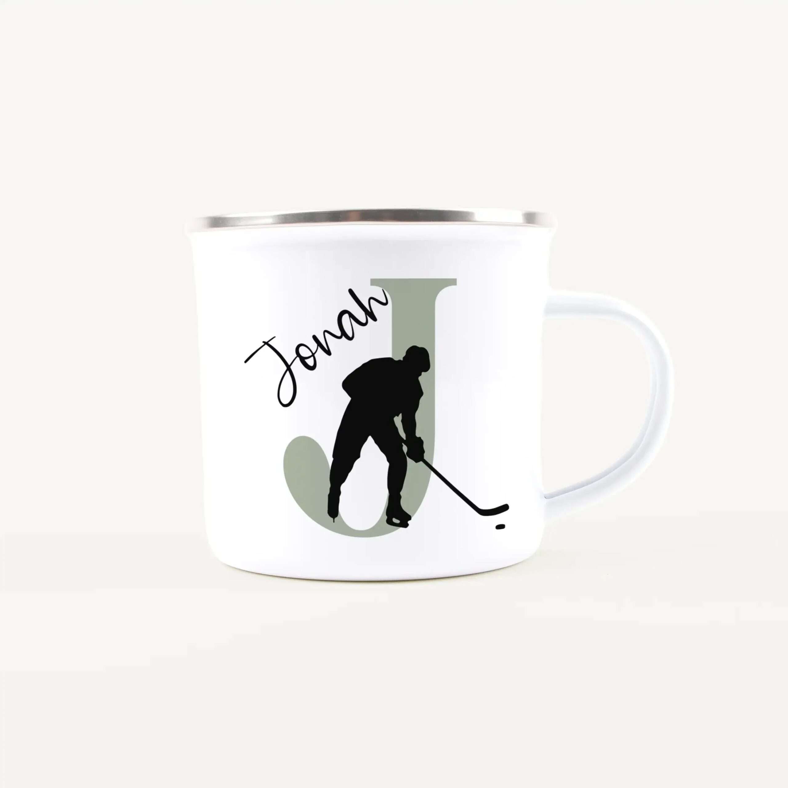 White mug featuring a black skier silhouette against a light green backdrop with cursive text partially visible on the left side.
