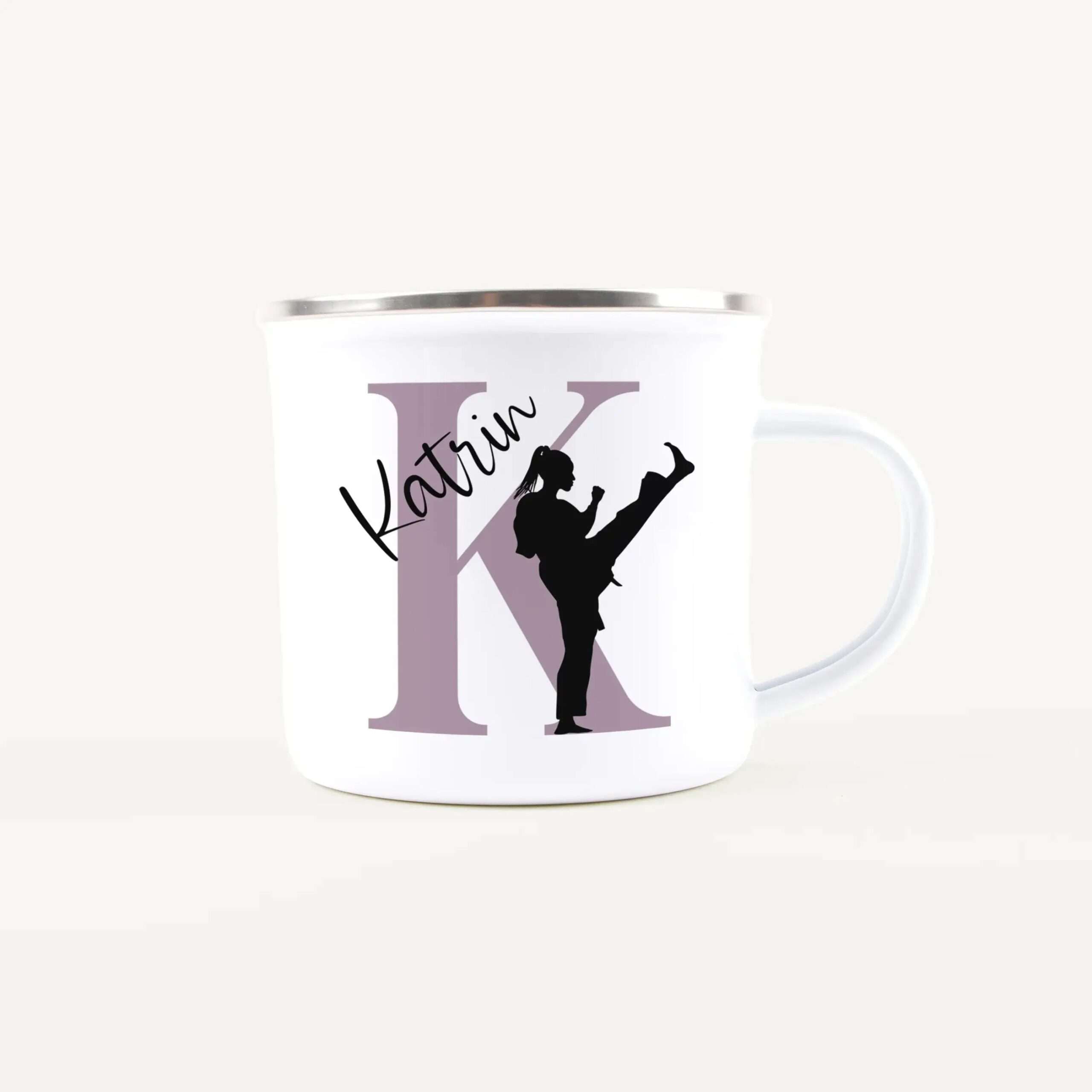 White ceramic mug with a large lavender letter K and black dancing silhouettes wrapped around the side, graphic design visible on the mug.