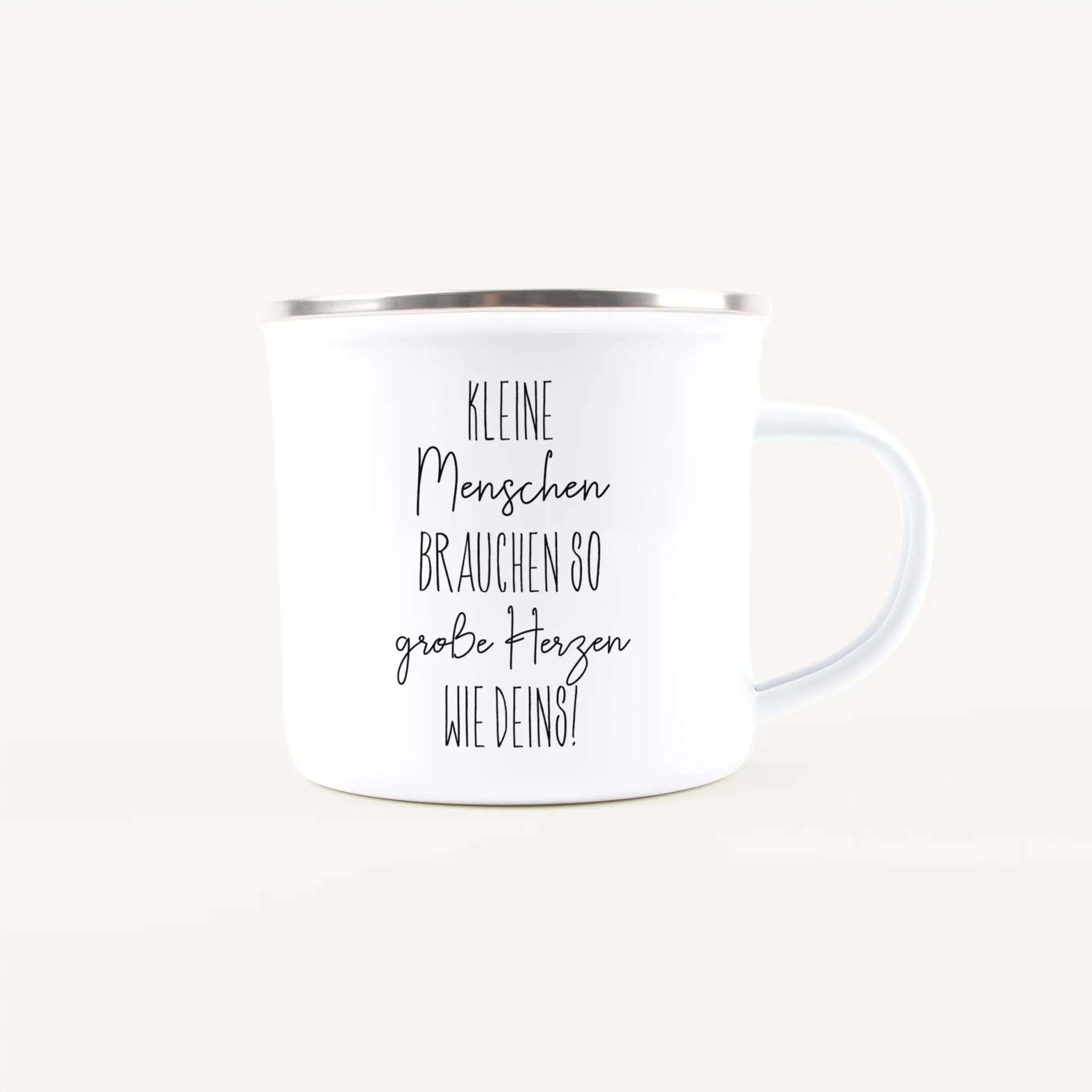 Close-up of a white mug with black handwritten German text on its surface, starting with 'Kleine Menschen ...'