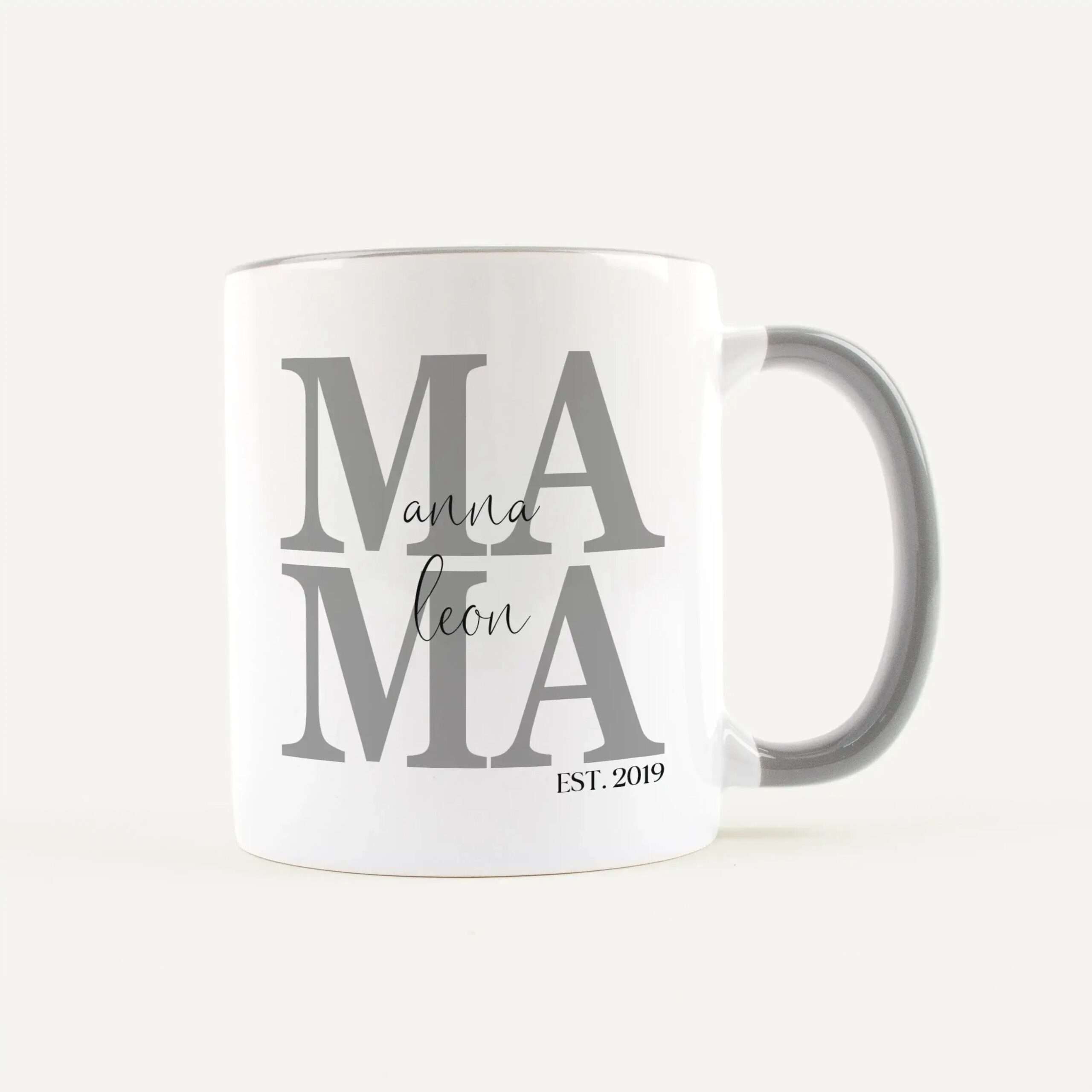 White ceramic mug featuring large gray 'MAMA' typography on the front, with a small cursive 'mama' overlay and EST. 2019 text at the bottom scroll area.