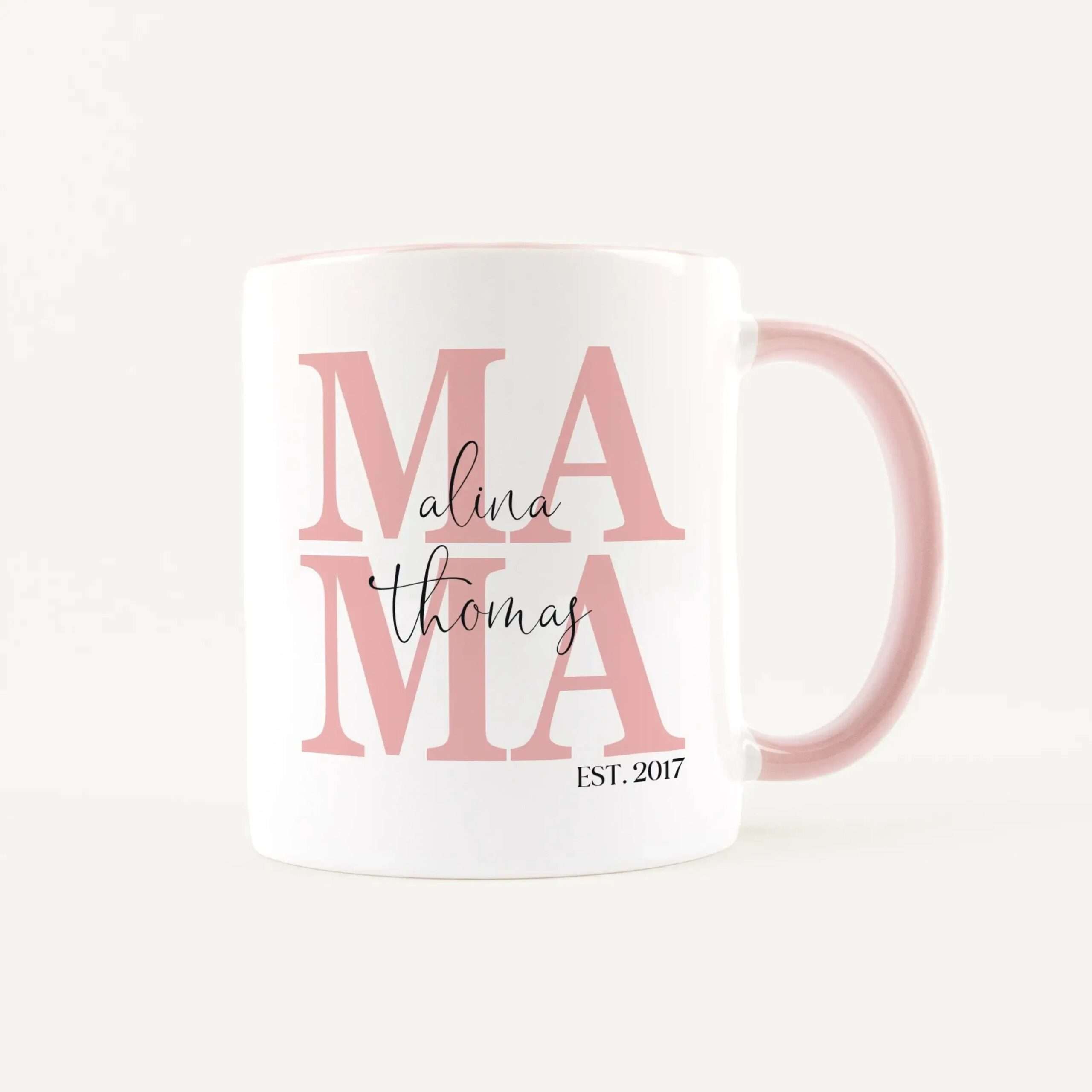 White ceramic mug with large pink 'MAMA' lettering and black script reading 'Malina Thomas' on the front, plus 'EST. 2017' at the bottom.