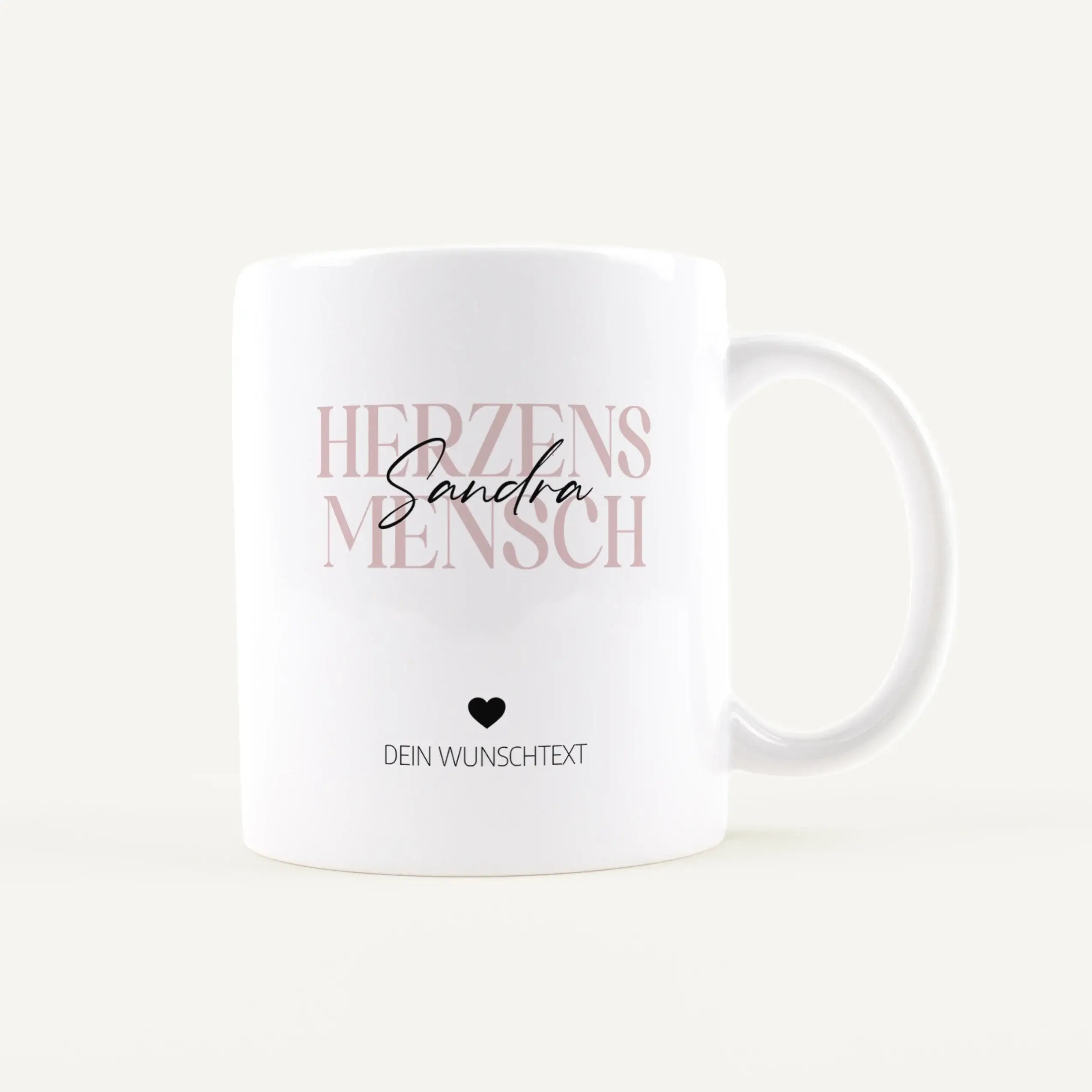 White mug featuring large pink text reading 'HERZEN' with a black cursive name over it, a small heart icon, and the placeholder 'DEIN WUNSCHTEXT' below.