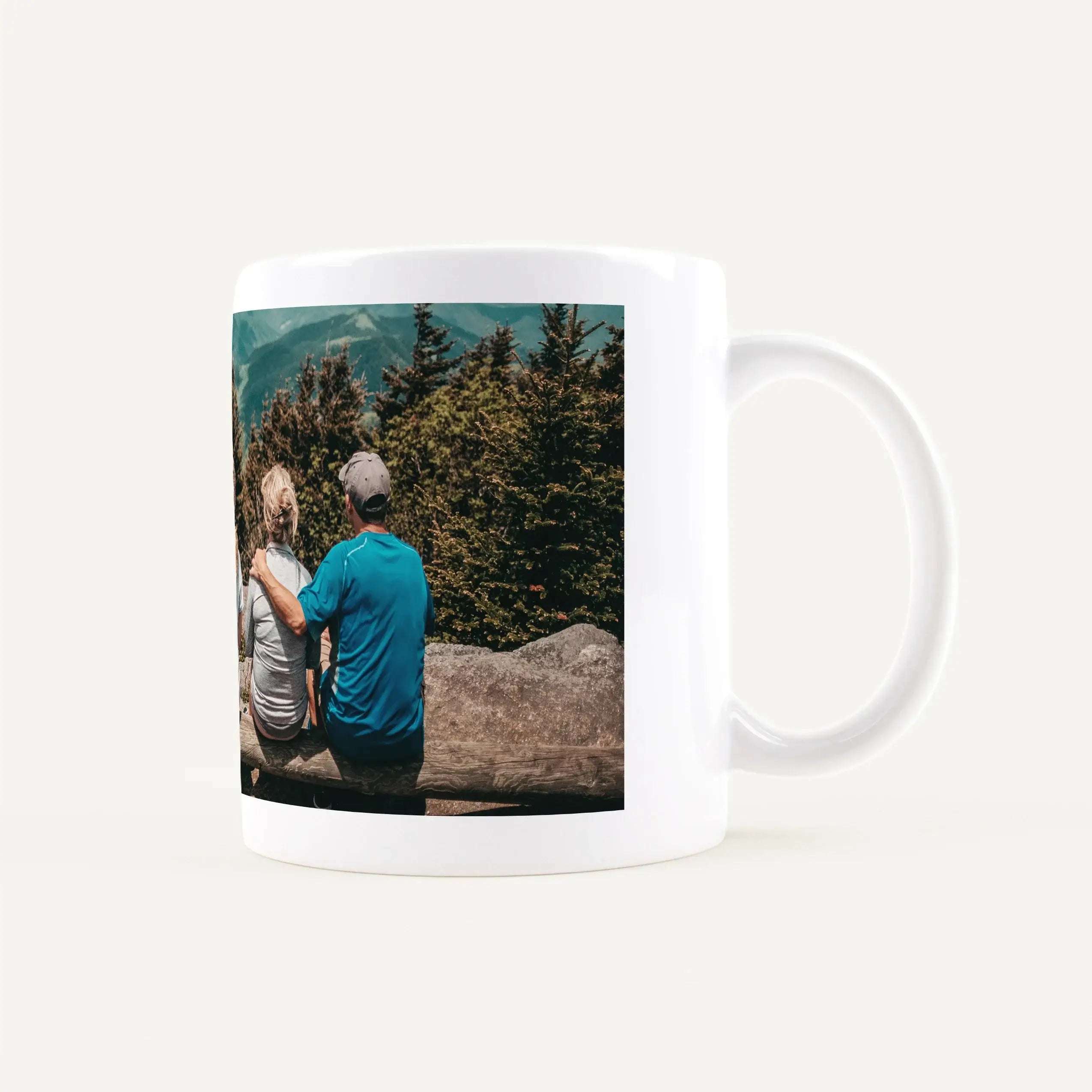 White ceramic mug featuring a wraparound photo of two hikers in a forested mountain landscape.