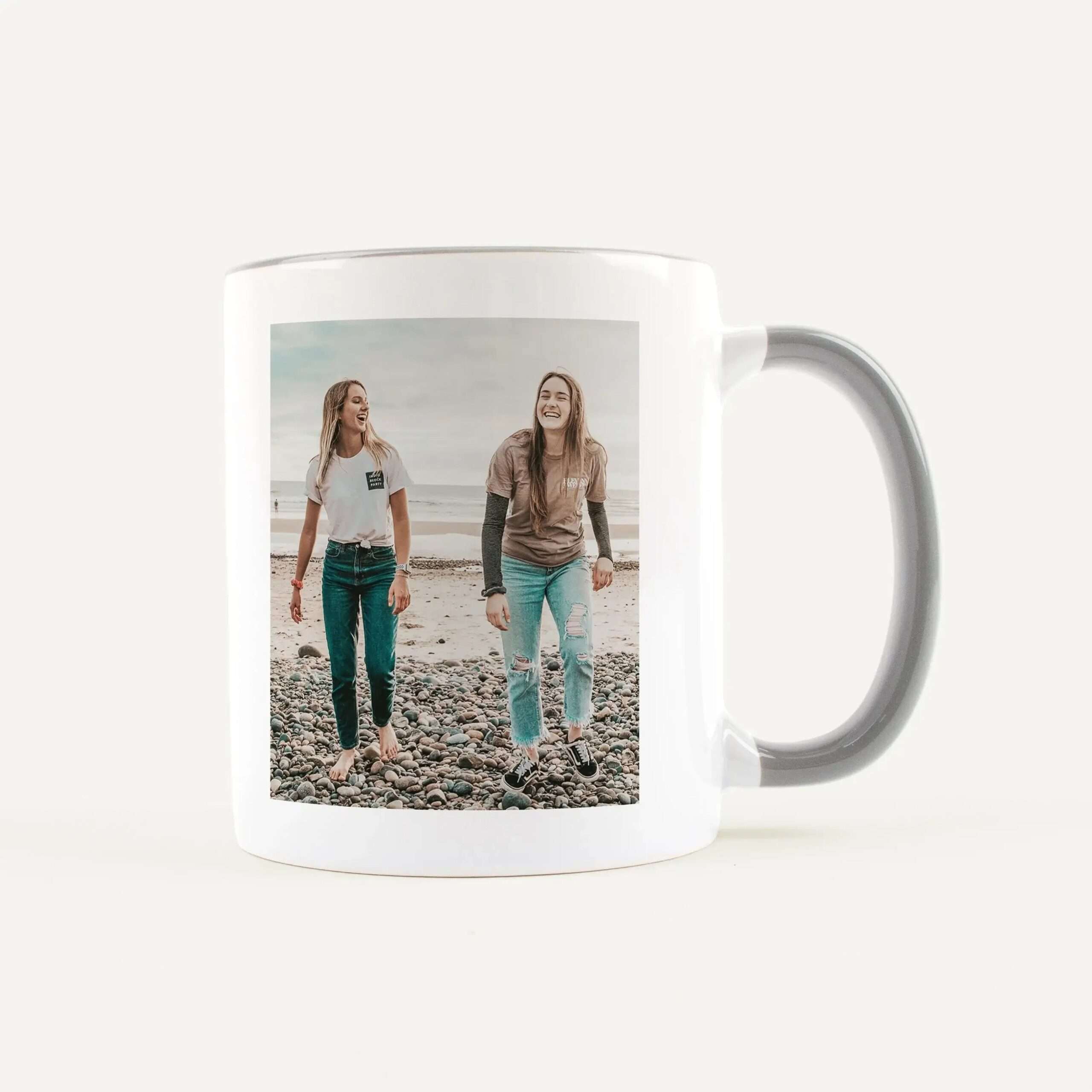 White mug with a printed photo of three friends smiling on a rocky beach.