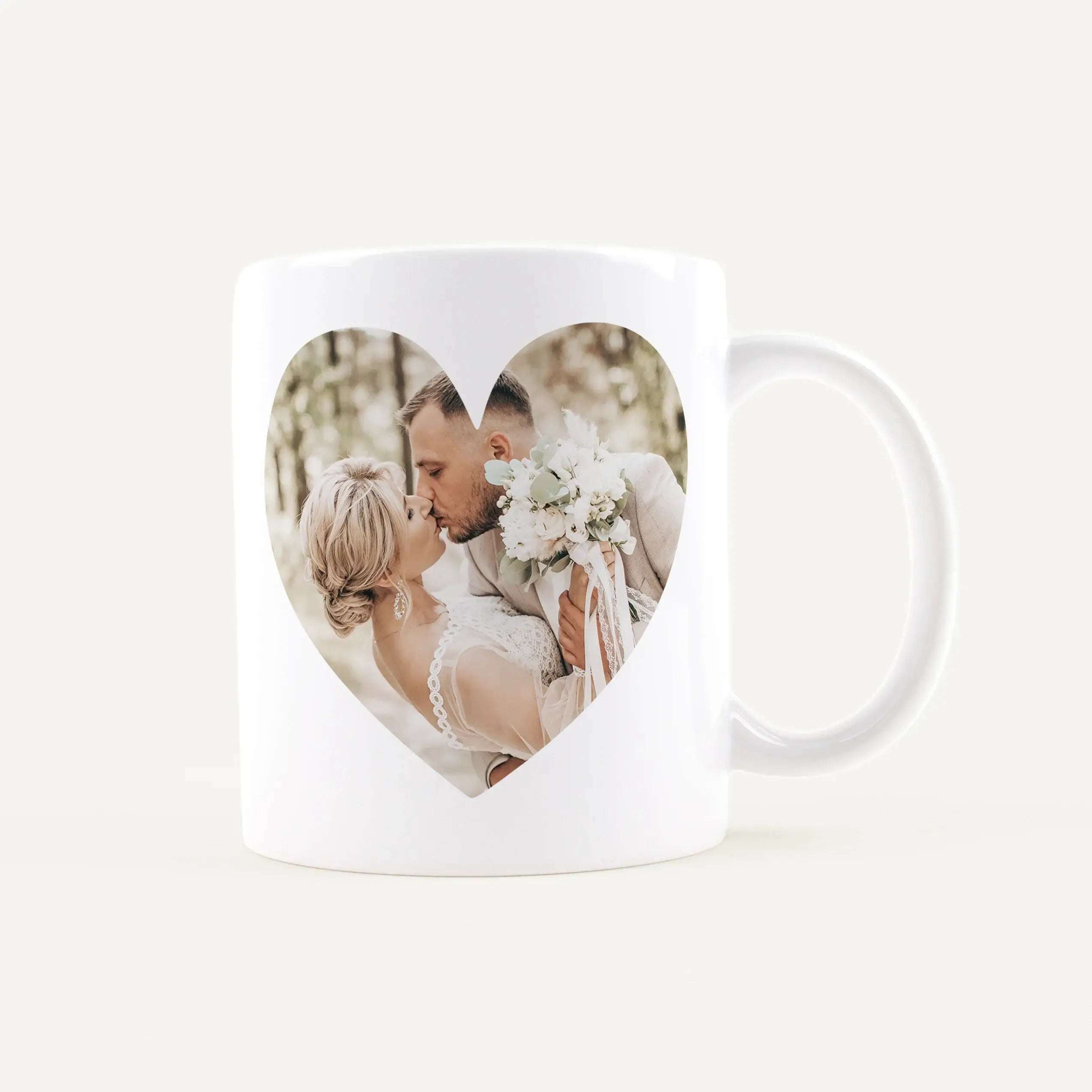 White mug with a heart-shaped window showing a couple kissing at a wedding, bouquet in view.