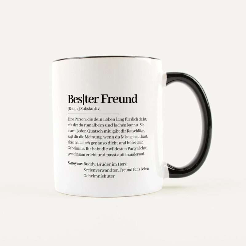 White ceramic mug with black handle, printed with a German dictionary-style entry and text on its side (visible word resembles 'Bestler Freund').