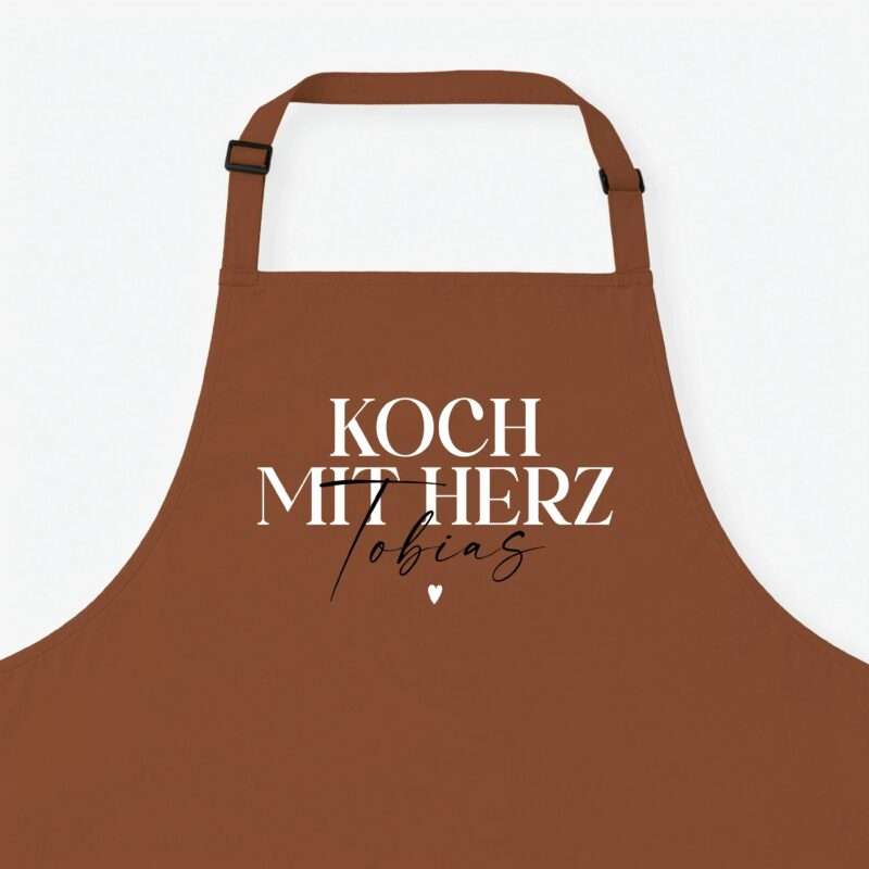 Brown apron with adjustable straps and black buckles displayed against a pale background; large white text overlays the front.