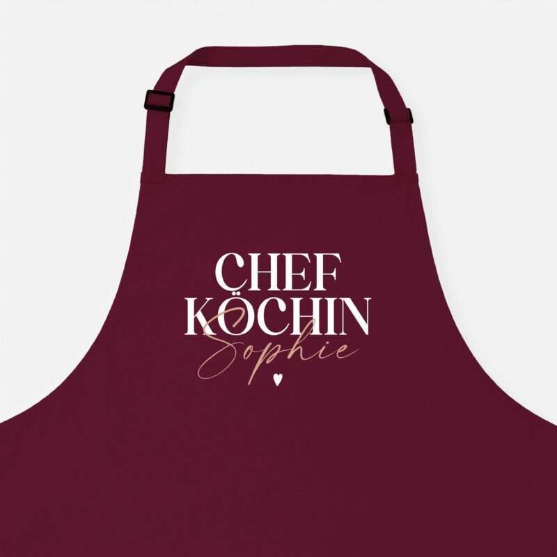 Close-up of a burgundy apron with white serif text reading 'CHEF KOCHIN' and a small heart symbol at the bottom.