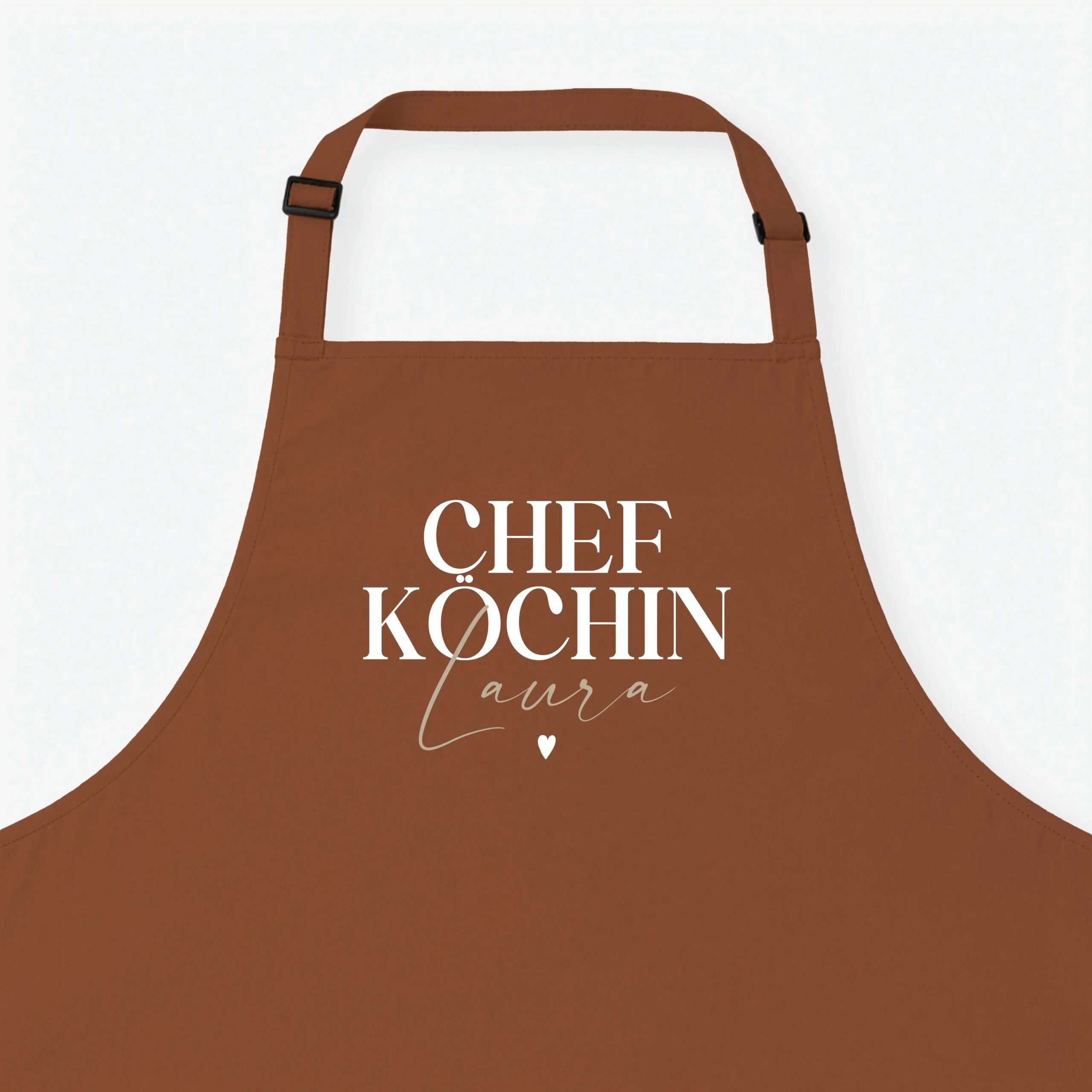 Brown apron with an adjustable neck strap, visible stitching, and white script text that reads 'CHEF KOCHIN' on a light background.