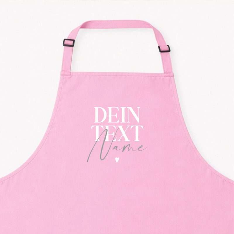 Close-up of a pink apron with adjustable straps and black buckles on a light background.
