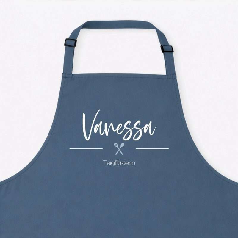 Blue apron with white cursive text reading 'Vanessa' and a small scissors icon beneath, set against a light background.