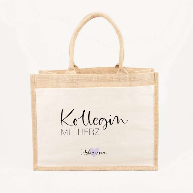 Beige burlap tote bag with handwritten script text and a small purple heart, handles visible at the top.