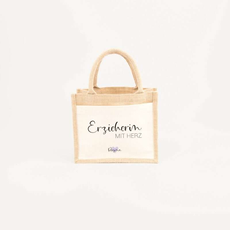 Beige burlap tote bag with printed text, partially reading 'Erzieherin' and 'MIT HERZ' on a light background.