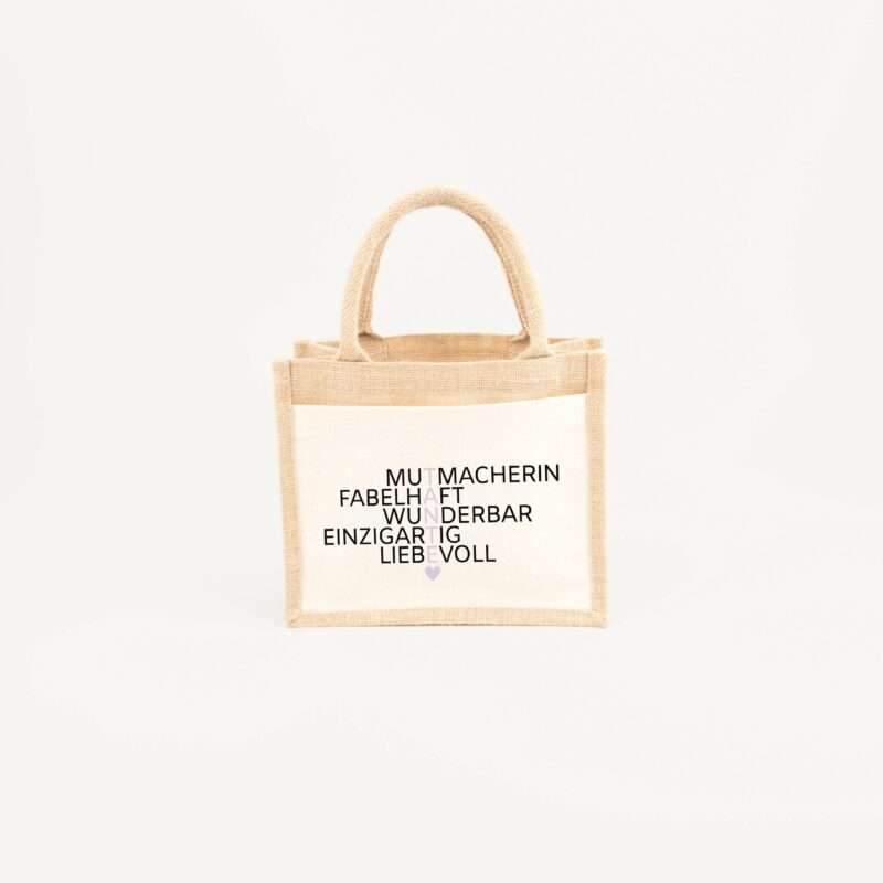 Beige burlap tote bag with two handles and bold German words on the front, a small purple heart at the bottom.
